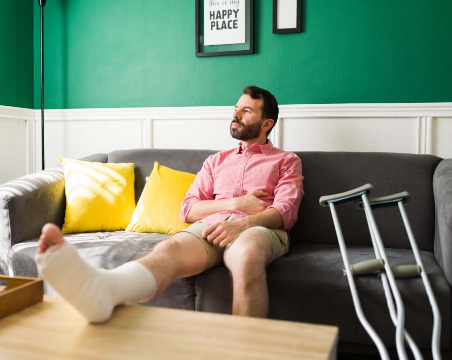 man sitting on couch with broken leg and crutches